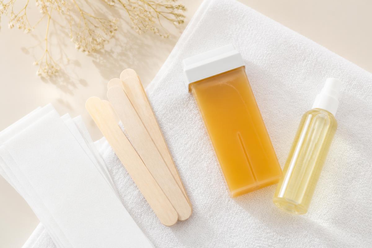 Kit de depilação com cera roll-on, espátulas e tiras sobre toalha branca